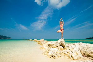 Hot summer yoga session on a beach - tropical Koh Phangan island, Thailand. Vriksha-asana - tree pose.